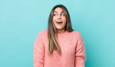 Güzel İspanyol bir kadın şaşkın, mutlu, şaşkın ve şaşırmış hissediyor, ağzı açık bir şekilde yana bakıyor.