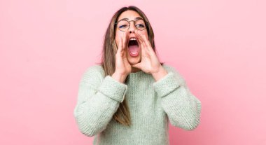 Güzel İspanyol bir kadın mutlu, heyecanlı ve pozitif hissediyor. Elleri ağızda, bağırarak bağırıyor.