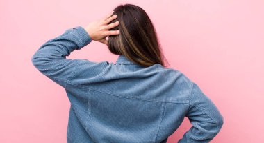 Düşünen, kuşkulanan, kafasını kaşıyan, kafası karışmış, kafası karışmış, arkadan ya da arkadan bakan İspanyol bir kadın.