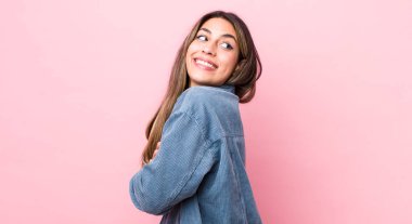 Güzel İspanyol kadın neşeyle gülümsüyor, mutlu, tatmin olmuş ve rahatlamış hissediyor, kollarını kavuşturup yan tarafa bakıyor.