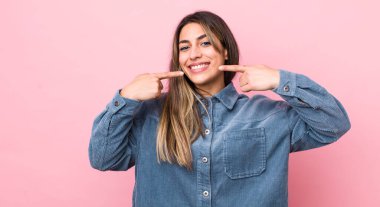 Güzel İspanyol kadın, kendine güvenerek gülümsüyor. Geniş bir gülümseme, pozitif, rahat, tatmin olmuş bir tavır sergiliyor.