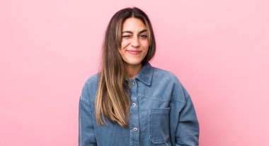 Güzel İspanyol bir kadın mutlu ve arkadaş canlısı görünüyor, gülümsüyor ve sana olumlu bir tavırla göz kırpıyor.