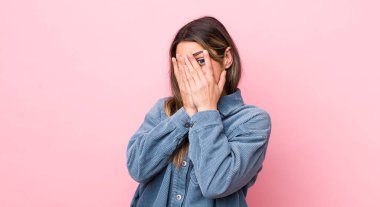 Güzel İspanyol bir kadın korkmuş ya da utanmış hissediyor. Gözleri yarı kapalı ya da elleri kapalı gözetliyor.