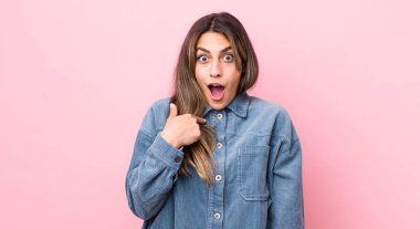 Şok olmuş ve ağzı açık, kendini işaret eden güzel İspanyol bir kadın.