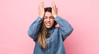 Güzel İspanyol bir kadın stresli ve endişeli, depresif ve hayal kırıklığına uğramış hissediyor, iki elini de başa kaldırıyor.