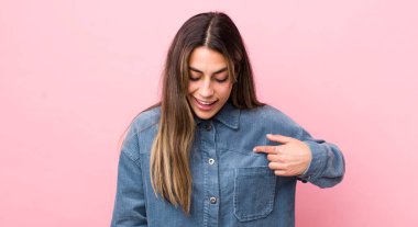 Güzel İspanyol kadın neşeyle gülümsüyor, yere bakıyor ve göğsüne işaret ediyor.