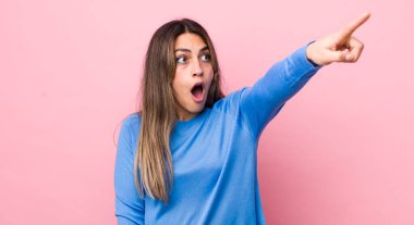 Oldukça İspanyol bir kadın şaşkın ve şaşırmış hissediyor, şaşırmış ve hayranlıkla yukarı bakıyor, şaşkın, açık ağızlı bir bakışla