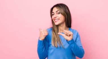 Güzel İspanyol kadın neşeyle gülümsüyor ve yan taraftaki fotokopi alanını gösteriyor, mutlu ve tatmin olmuş hissediyor.