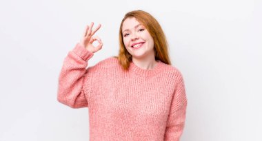 Güzel kızıl saçlı kadın mutlu, rahat ve tatmin olmuş hissediyor. Onayını iyi bir hareketle gösteriyor. Gülümsüyor.