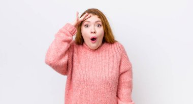 Güzel kızıl saçlı kadın mutlu, şaşkın ve şaşırmış görünüyor, gülümsüyor ve inanılmaz ve inanılmaz iyi haberleri fark ediyor.