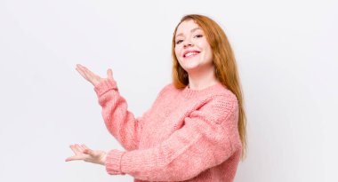 Güzel kızıl saçlı kadın gururla ve güvenle gülümsüyor, mutlu ve tatmin olmuş hissediyor ve fotokopi alanında bir konsept gösteriyor.