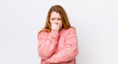 Güzel kızıl saçlı kadın ciddi, düşünceli ve endişeli, elleri çenesine bastırılmış şekilde yan bakıyor.