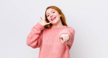 Güzel kızıl saçlı kadın neşeyle gülümsüyor ve kamerayı işaret ediyor. Sonra seni arıyor, telefonla konuşuyor.