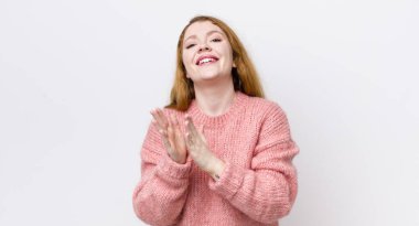 Güzel kızıl saçlı kadın mutlu ve başarılı hissediyor, gülümsüyor ve alkışlıyor, alkışlarla tebrik ediyor.