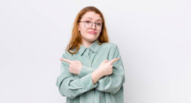 Güzel kızıl saçlı kadın şaşkın ve şaşkın görünüyor, güvensiz ve şüpheleri olan zıt yönleri işaret ediyor.