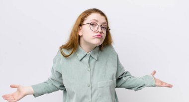 pretty red head woman feeling clueless and confused, having no idea, absolutely puzzled with a dumb or foolish look