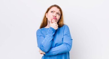 Güzel kızıl saçlı kadın düşünüyor, kuşkulu ve şaşkın hissediyor, farklı seçeneklerle, hangi kararı vereceğini merak ediyor.