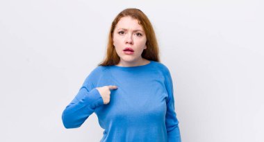 Güzel kızıl saçlı kadın şaşkın, şaşkın ve güvensiz hissediyor, kendini gösterip kim olduğunu soruyor, ben mi??