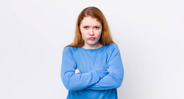 Güzel kızıl saçlı kadın hayal kırıklığına uğramış ve hayal kırıklığına uğramış, ciddi görünüyor, kızgın ve kollarını kavuşturmuş.