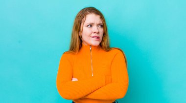 Güzel kızıl saçlı kadın şüphe ediyor ya da düşünüyor, dudağını ısırıyor ve kendini güvensiz ve gergin hissediyor, kenarda yer arıyor.