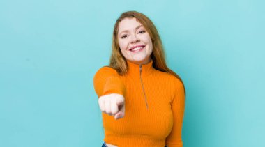 Güzel kızıl saçlı kadın kameraya bakıyor. Tatmin olmuş, kendine güvenen, dost canlısı bir gülümsemeyle. Seni seçiyor.