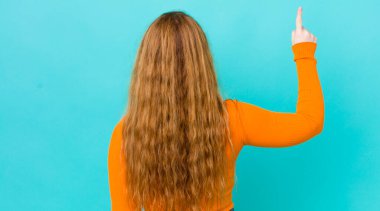 Güzel kızıl saçlı kadın dikiz aynasındaki nesneyi işaret ediyor.