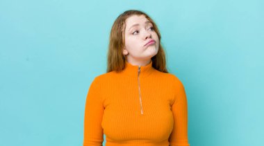 Güzel kızıl saçlı kadın endişeli, kafası karışık, budala bir ifadeyle, kopya alanı arıyor, şüpheci