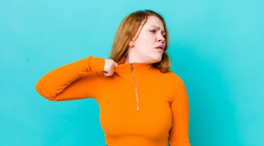 Güzel kızıl saçlı kadın stresli, endişeli, yorgun ve hayal kırıklığına uğramış, gömleğini çekiştiren, sorunlardan bıkmış görünüyor.