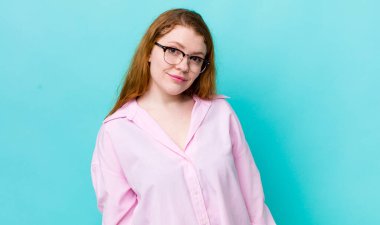 Güzel kızıl saçlı kadın gururlu, kendinden emin, havalı, küstah ve küstah görünüyor, gülümsüyor, başarılı hissediyor.