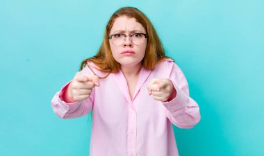 Güzel kızıl saçlı kadın kamerayı iki parmağıyla ve kızgın bir ifadeyle sana görevini yapmanı söylüyor.