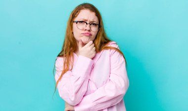 Güzel kızıl saçlı kadın ciddi görünüyor, kafası karışık, kararsız ve düşünceli, seçenekler ve seçimler arasında şüpheci.