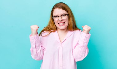 Güzel kızıl saçlı kadın mutlu, şaşırmış ve gururlanmış hissediyor, bağırıyor ve başarıyı büyük bir gülümsemeyle kutluyor.