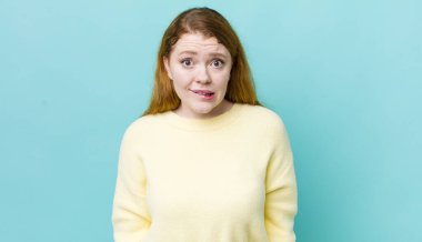 Güzel kızıl saçlı kadın şaşkın ve şaşkın görünüyor. Sinirli bir hareketle dudağını ısırıyor. Sorunun cevabını bilmiyor.