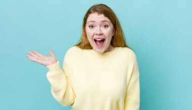 Güzel kızıl saçlı kadın mutlu, şaşkın ve neşeli, pozitif bir tavırla gülümsüyor, bir çözüm ya da fikri fark ediyor.