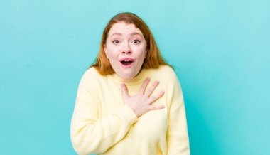 Güzel kızıl saçlı kadın şaşkın ve şaşırmış hissediyor, gülümsüyor, el ele tutuşuyor, o olmaktan mutlu ya da minnettarlık gösteriyor.