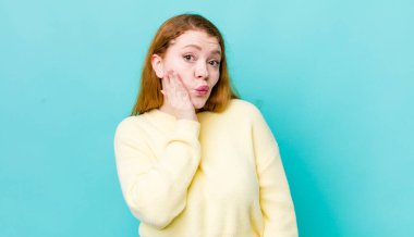 Güzel kızıl saçlı kadın şaşkın ve şaşkın hissediyor. Ağzı açık, yüz yüze inançsızlık içinde.