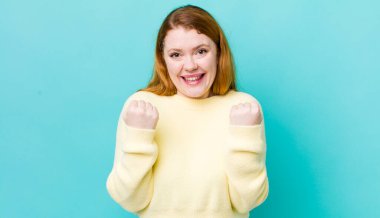 Güzel kızıl saçlı kadın zaferle bağırıyor, gülüyor, mutlu ve heyecanlı hissediyor başarıyı kutlarken.