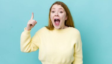 Güzel kızıl saçlı kadın bir fikri fark ettikten sonra kendini mutlu ve heyecanlı bir dahi gibi hissediyor, neşeli bir şekilde parmağını kaldırıyor, eureka!