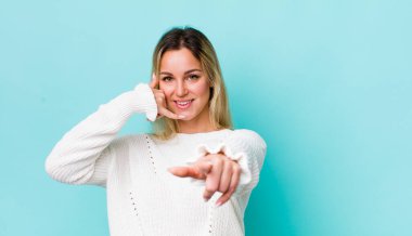 Güzel sarışın kadın neşeyle gülümsüyor ve kamerayı işaret ediyor. Sonra seni arıyor, telefonla konuşuyor.