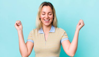 Güzel sarışın kadın son derece mutlu ve şaşırmış görünüyor, başarıyı kutluyor, bağırıyor ve zıplıyor.