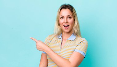 Güzel sarışın kadın heyecanlı ve şaşırmış görünüyor. Yana ve yukarıya doğru uzayı gösteriyor.