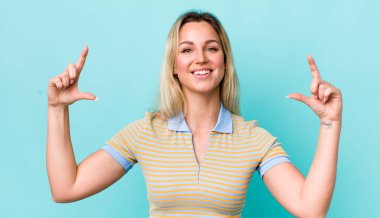 Güzel sarışın bir kadın kendi gülüşünü çiziyor, iki eliyle, olumlu ve mutlu görünüyor, sağIık kavramı.