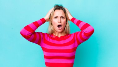 Güzel sarışın kadın dehşete kapılmış ve şok olmuş hissediyor, ellerini havaya kaldırıyor ve hata yaptığında panikliyor.