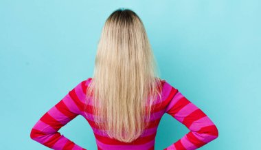 Güzel sarışın kadın kafası karışık ya da dolgun hissediyor ya da şüphe ve sorular, merak ediyor, elleri kalçasında, dikiz aynasından.