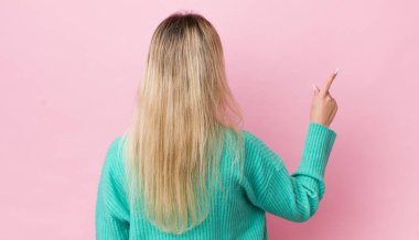 Güzel sarışın kadın dikiz aynasındaki objeyi işaret ediyor.