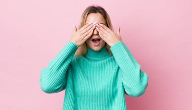 Güzel sarışın kadın gülümsüyor ve mutlu hissediyor, iki eliyle gözlerini kapatıyor ve inanılmaz bir sürpriz bekliyor.