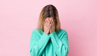 Güzel sarışın kadın üzgün, hayal kırıklığına uğramış, gergin ve depresif, iki eliyle yüzünü kaplayan, ağlayan