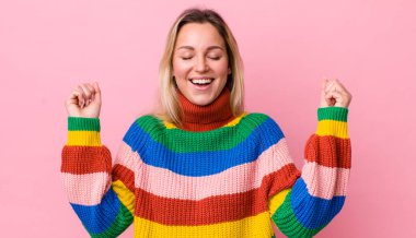 Güzel sarışın kadın son derece mutlu ve şaşırmış görünüyor, başarıyı kutluyor, bağırıyor ve zıplıyor.