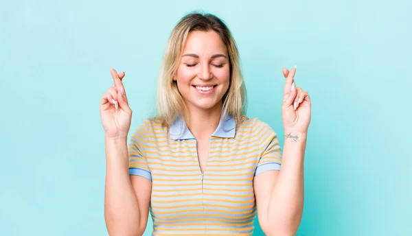 Bonita Mujer Rubia Sonriendo Ansiosamente Cruzando Ambos Dedos Sintiéndose Preocupada —  Fotos de Stock