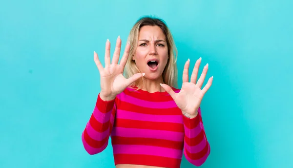 pretty blonde woman feeling terrified, backing off and screaming in horror and panic, reacting to a nightmare